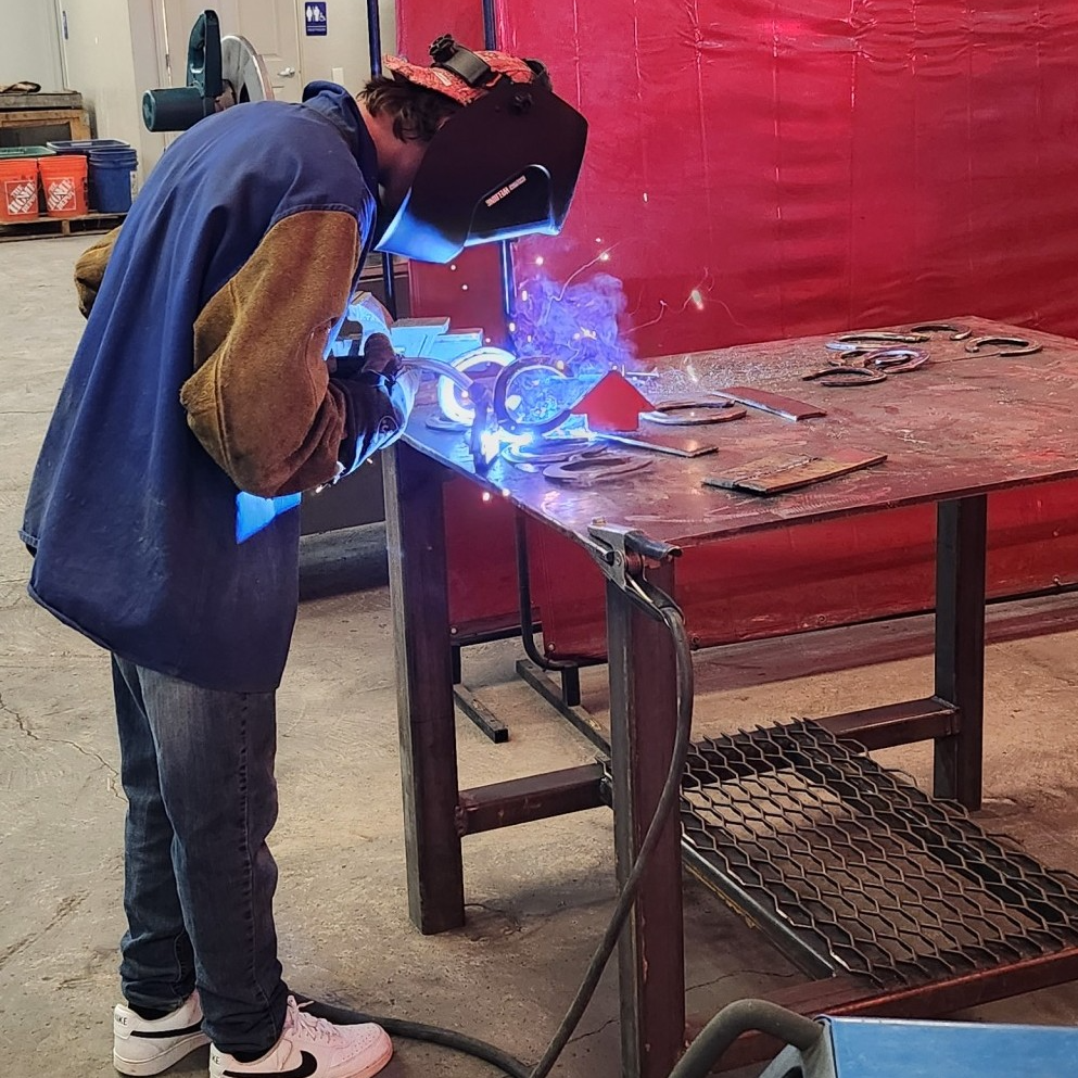 Image of student welding wearing protective gear.